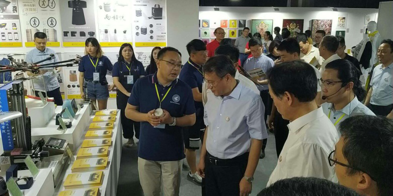 西安市委常委、副市长高杲在青博会听取明德学院师生讲解设计作品